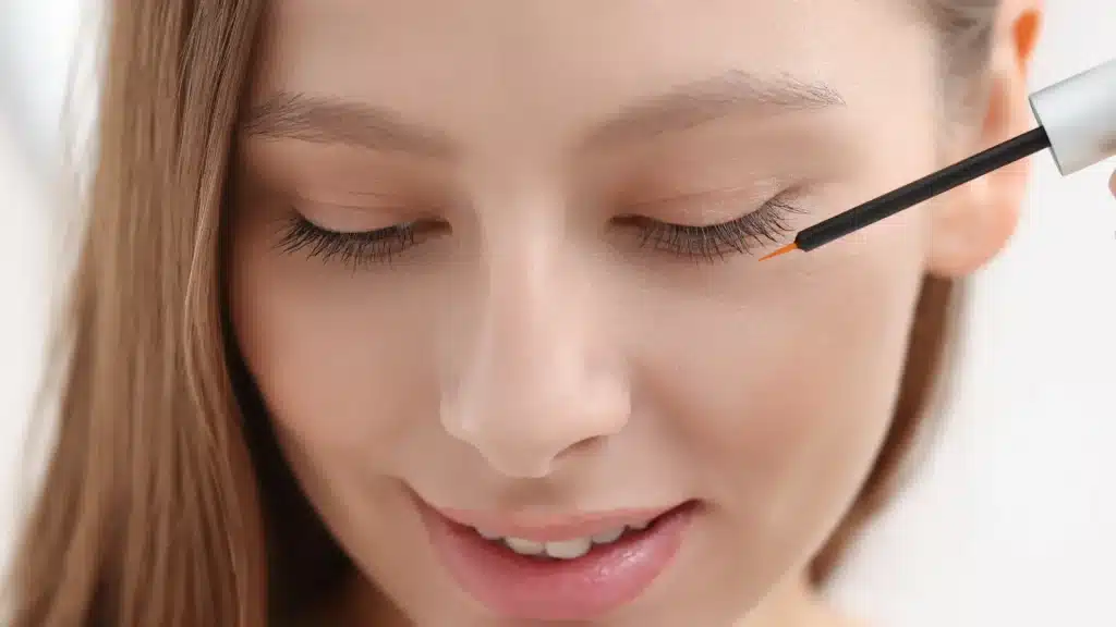An individual applying serum to their eyelashes.