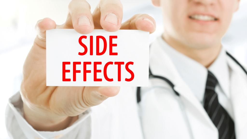 A doctor in a white coat holds a small white card with the words "SIDE EFFECTS" written in bold red letters. The doctor's face is slightly blurred and out of focus, emphasizing the card being held up toward the camera.