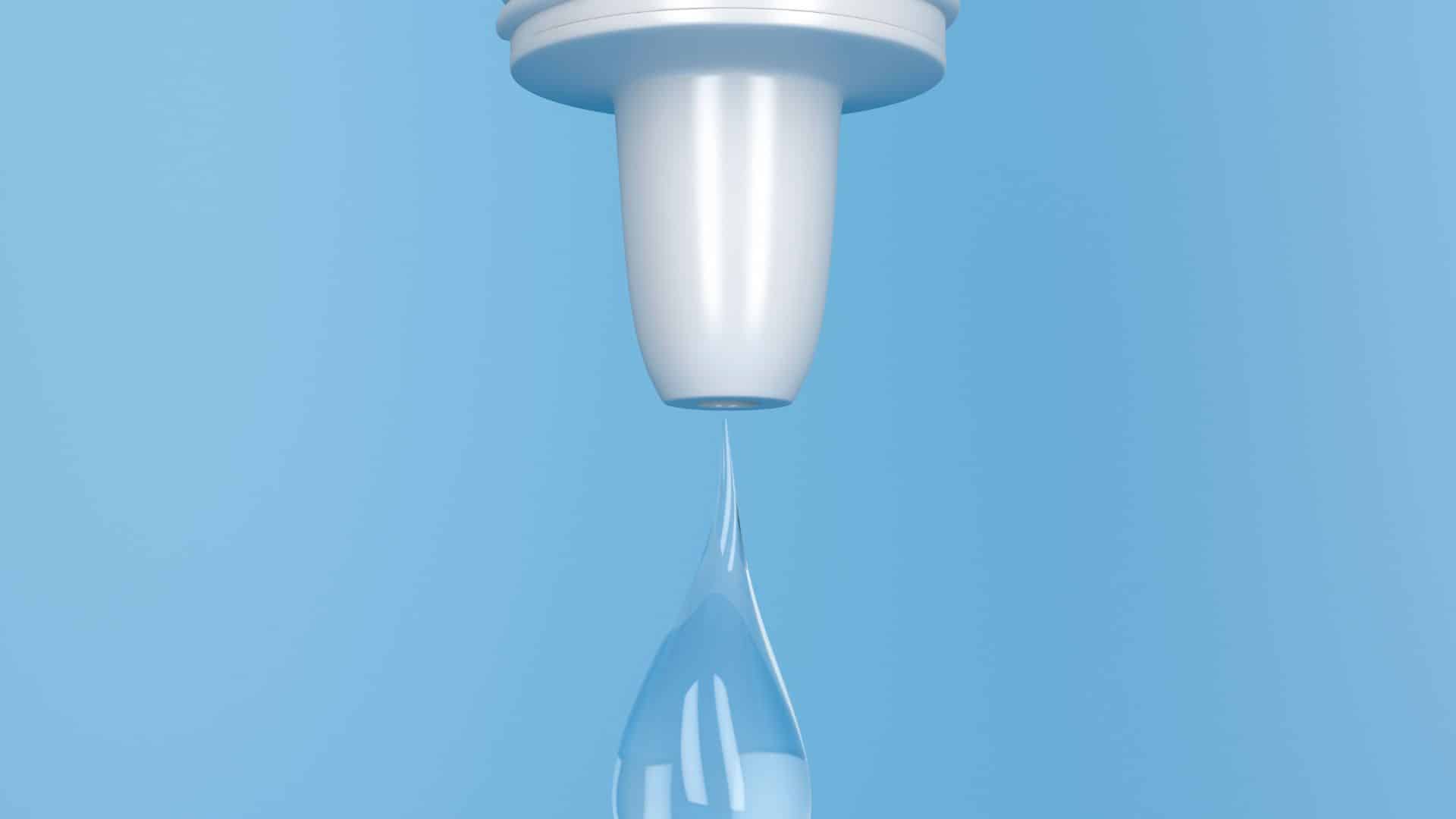 Close-up of a white water filter against a light blue background, with a single droplet of clear water falling from the filter.