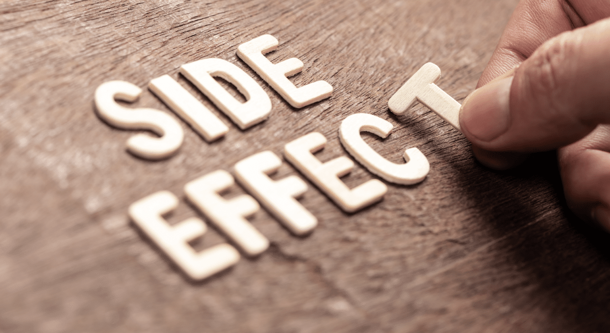 The image shows the phrase "SIDE EFFECT" in wooden letters on a textured wooden surface. A hand is placing the letter 'T' at the end of the word "EFFECT.