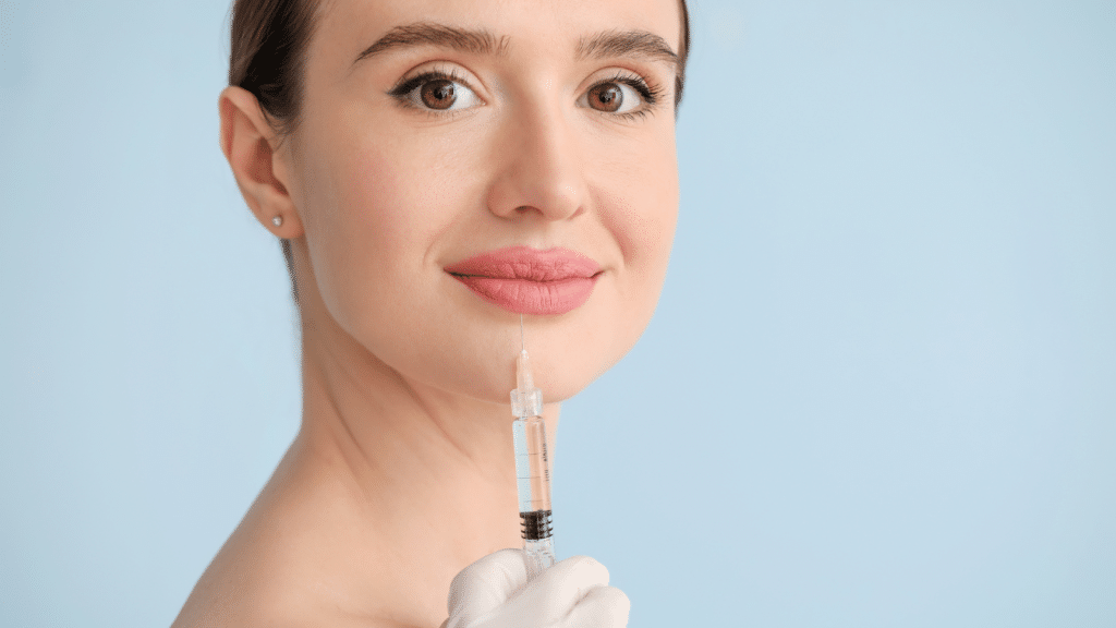 A woman with a serene expression holds a syringe near her lips. She wears a white glove, and the background is a light blue color.