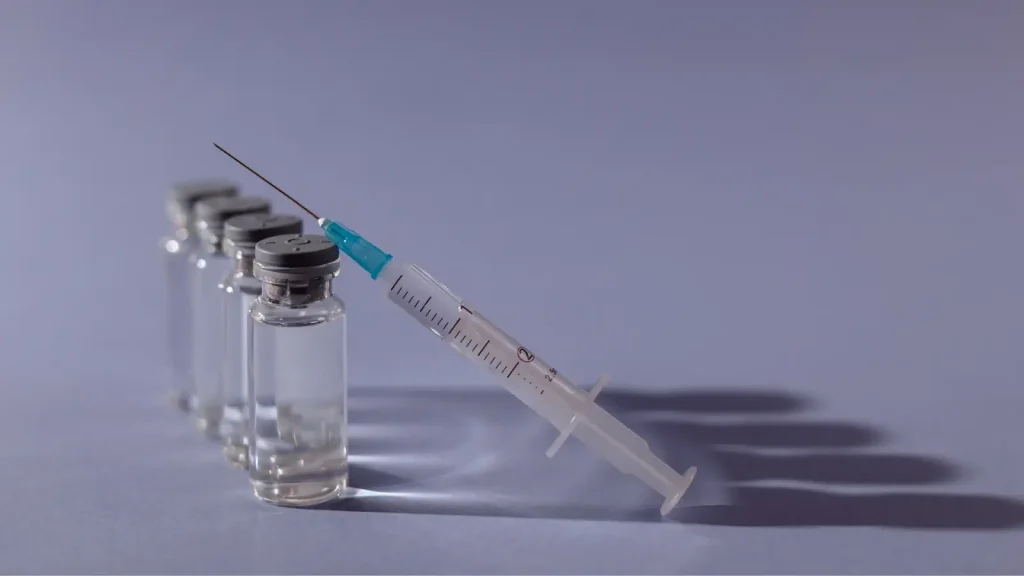 A syringe rests against vials.