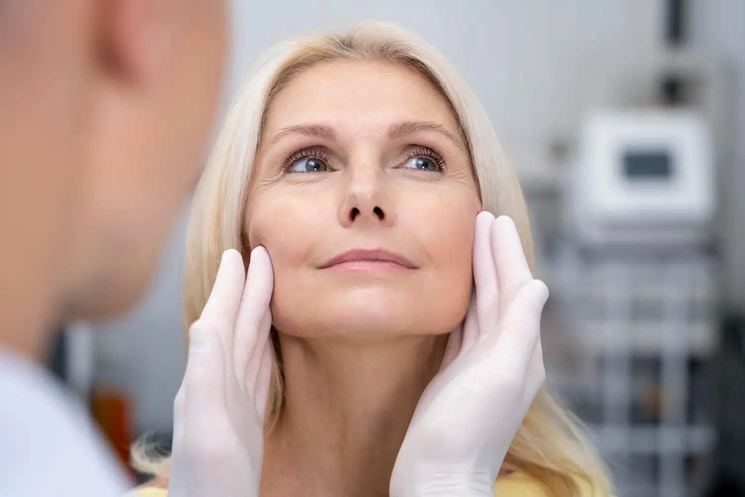 A healthcare professional assesses a patient's facial structure before treatment