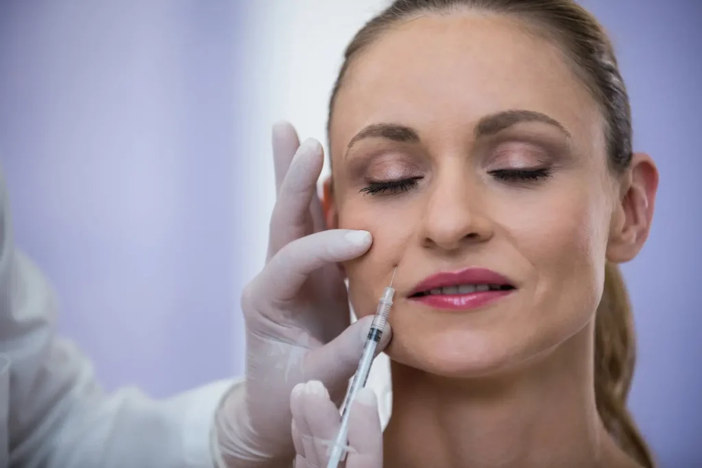 Close-up of a woman receiving a cosmetic injection on her cheek by a gloved professional