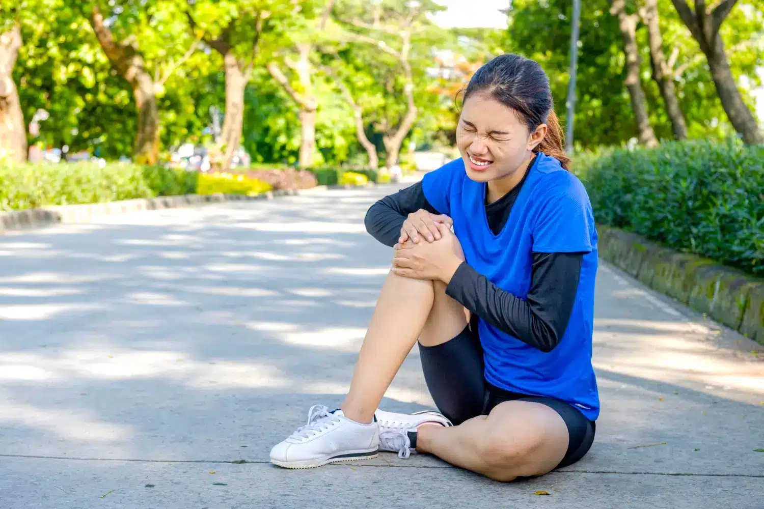 A woman cradles her knee after experiencing sudden joint pain.