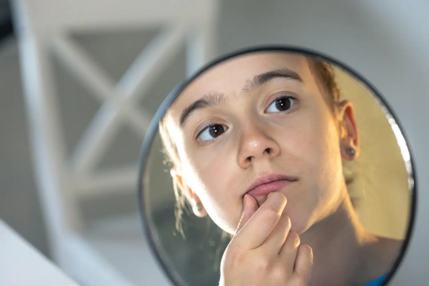 woman observes and looks at her lips in the mirror