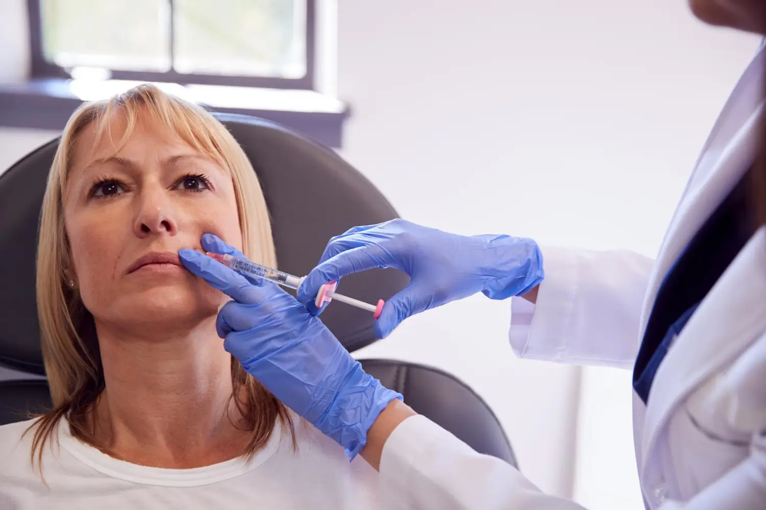 a woman receives filler treatment in a clinical setting