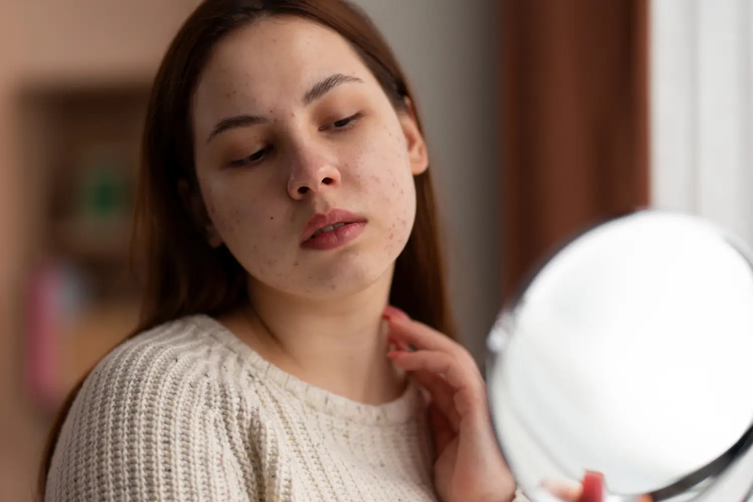 woman looking at skin in the mirror